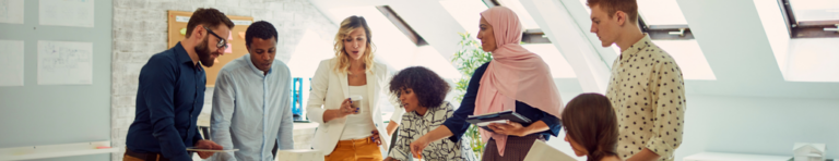 Diverse team of professionals stand around a table discussing ideas.