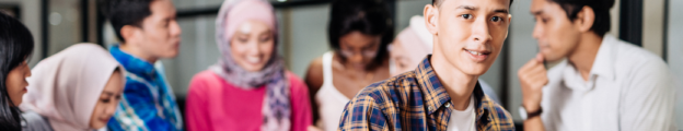 Diverse group of high school students stand and talk in a circle. A male student faces the camera.