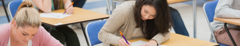 High school students sitting at desks handwriting.