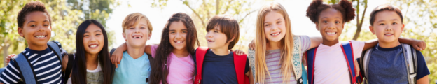 Diverse group of smiling children with theirs arms across each other's shoulders while outside.