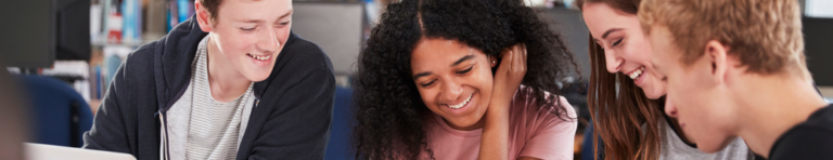 Diverse group of smiling high school students work on a group assignment.