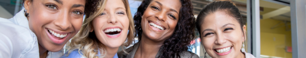 Group of four diverse, smiling professional women.