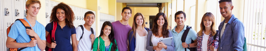 Diverse group of smiling high school students standing shoulder to shoulder in a school hallway lined with lockers.