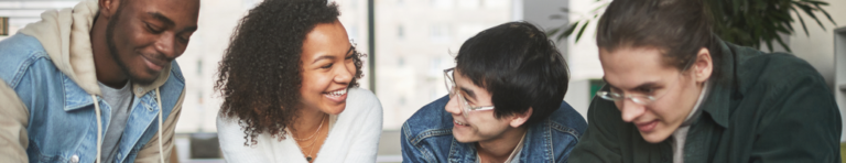 Diverse group of four high school students working and laughing with each other.