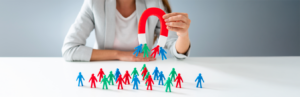 person holding magnet with small people figurines getting attached to the magnet